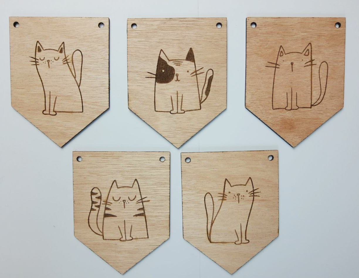 Vijf houten vlaggetjes met elk een andere illustratie van een kat. De vlaggetjes liggen naast elkaar