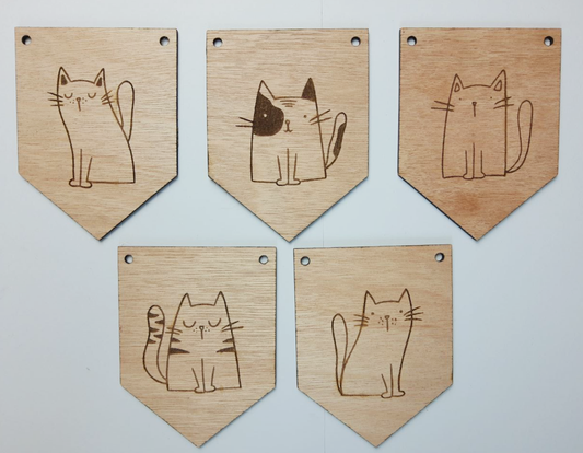 Vijf houten vlaggetjes met elk een andere illustratie van een kat. De vlaggetjes liggen naast elkaar