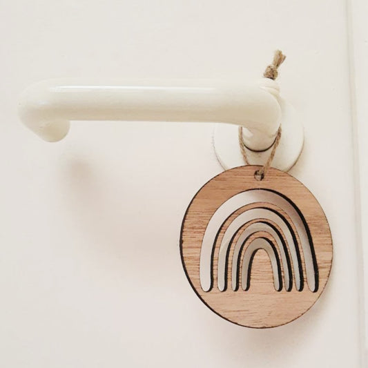 Regenbooghangertje dat met het jute touwtje aan een deurklink hangt. Hierdoor wordt het sleutelgat bedekt. 